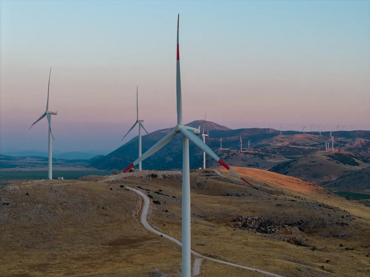 A scenic view of wind turbines on rolling hills at sunset, showcasing renewable energy.