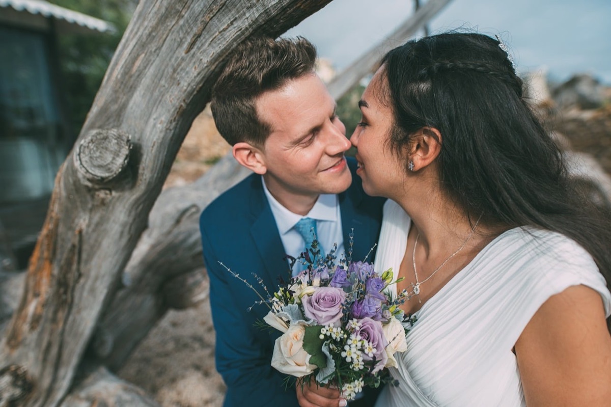 witte trouwkleed en tuxedo op een tropisch strand