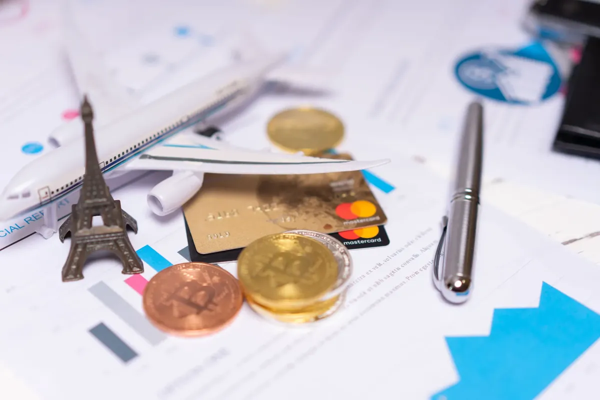 A travel finance concept featuring cryptocurrency, credit card, airplane model, and Eiffel Tower on financial documents.